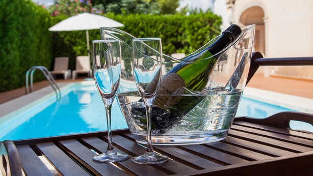 A poolside table with a champagne bottle, glasses, and a bowl of ice. - Villa Sa Coma - A Perfect Retreat for Your Dream Vacation! (Cala Millor)