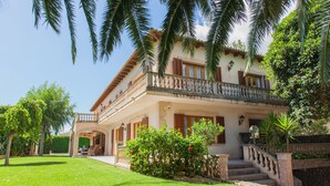 A two-story house with a balcony, a stone staircase, and a well-maintained lawn. - Villa Sa Coma - A Perfect Retreat for Your Dream Vacation! (Cala Millor)
