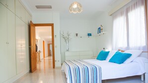 A bedroom with a large bed, a bedside table, a nightstand, a dresser, and a mirror. - Villa Sa Coma - A Perfect Retreat for Your Dream Vacation! (Cala Millor)