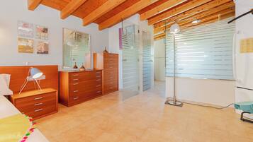 Une chambre avec un plafond en bois, un lit avec un oreiller blanc, une table de chevet, une commode et un miroir.