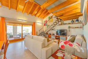 A spacious living room with a sofa, a TV, and a staircase leading to an upper level.