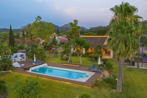 A residential area with a swimming pool, lounge chairs, and a well-maintained garden.