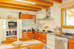 Una cocina con armarios de madera, horno empotrado, cafetera y ventana.