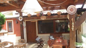 Eine Terrasse im Freien mit Holzmöbeln, einem Tisch und hängenden Pflanzgefäßen.