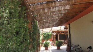 Ein überdachter Außenbereich mit einer Holz-Pergola, Topfpflanzen und Fahrrädern.