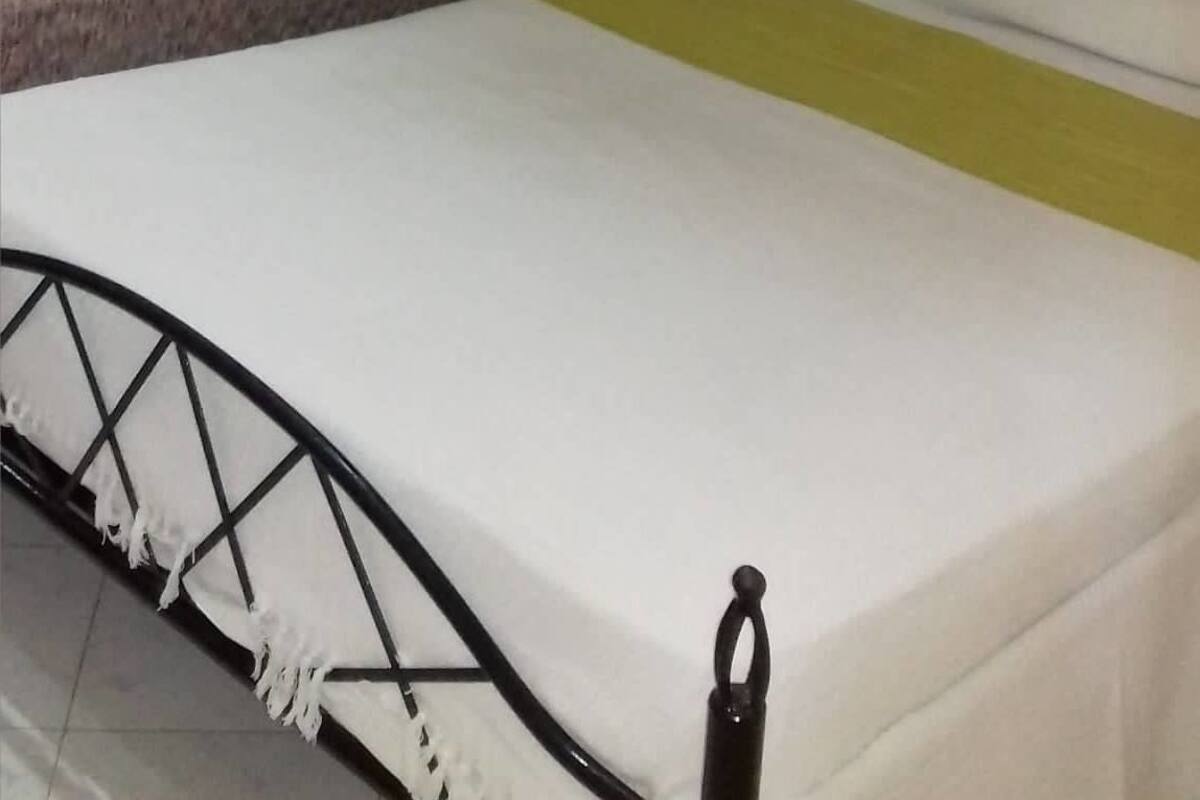 Une chambre à coucher avec un lit, une table de chevet, une lampe, un tableau au mur et une fenêtre avec des rideaux.