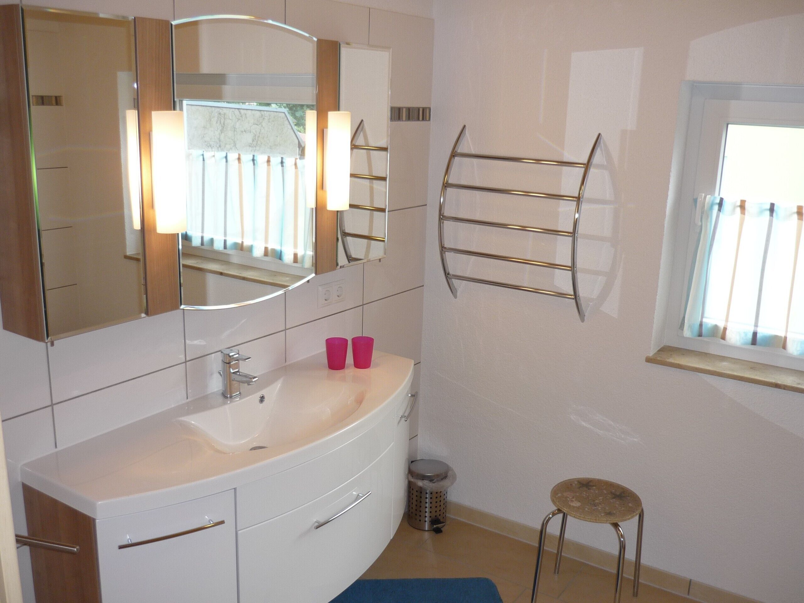Un bagno moderno con un mobile lavabo bianco, uno specchio grande e un porta asciugamani.