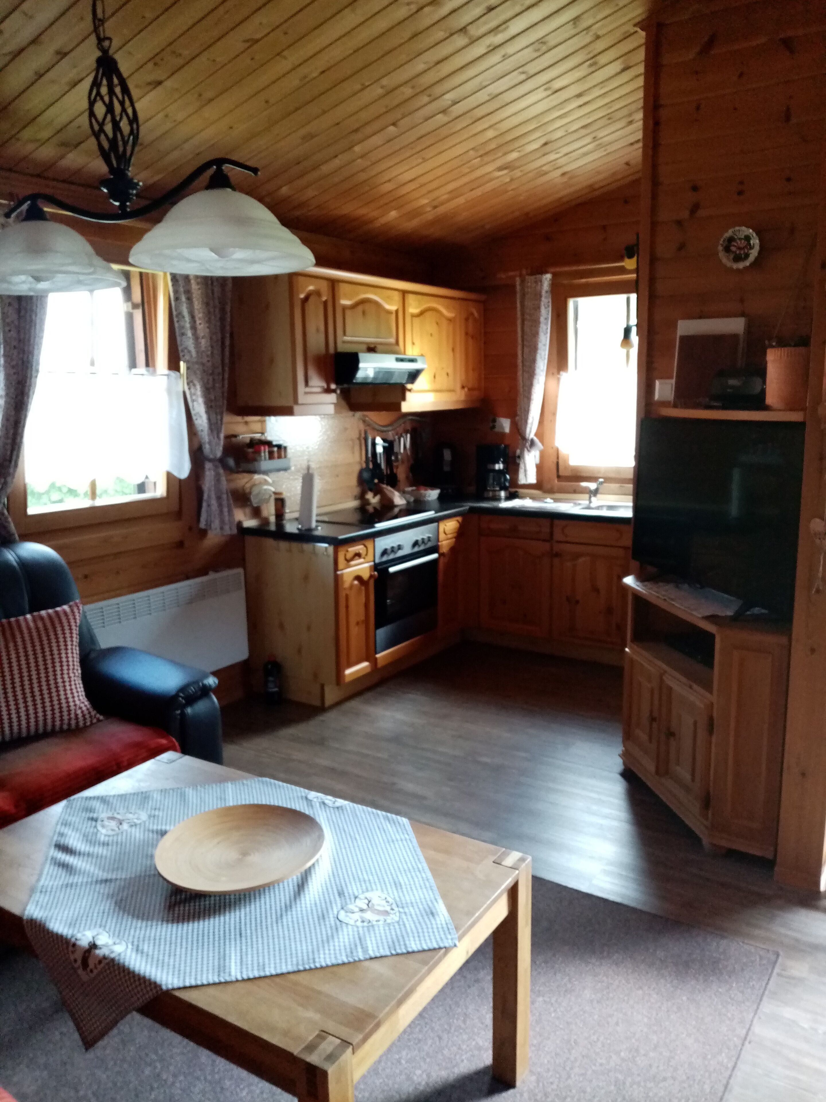Eine gemütliche Küchenzeile im Chalet-Stil mit Holzschränken, einem Essbereich mit Tisch und Stühlen sowie einem eingebauten Backofen.