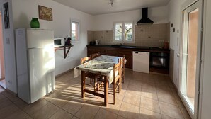 A kitchen with a dining table, chairs, a refrigerator, a microwave, a sink, and a window.