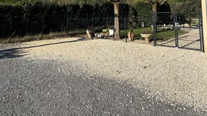 A gravel path leading to a fenced area with a bench and potted plants.