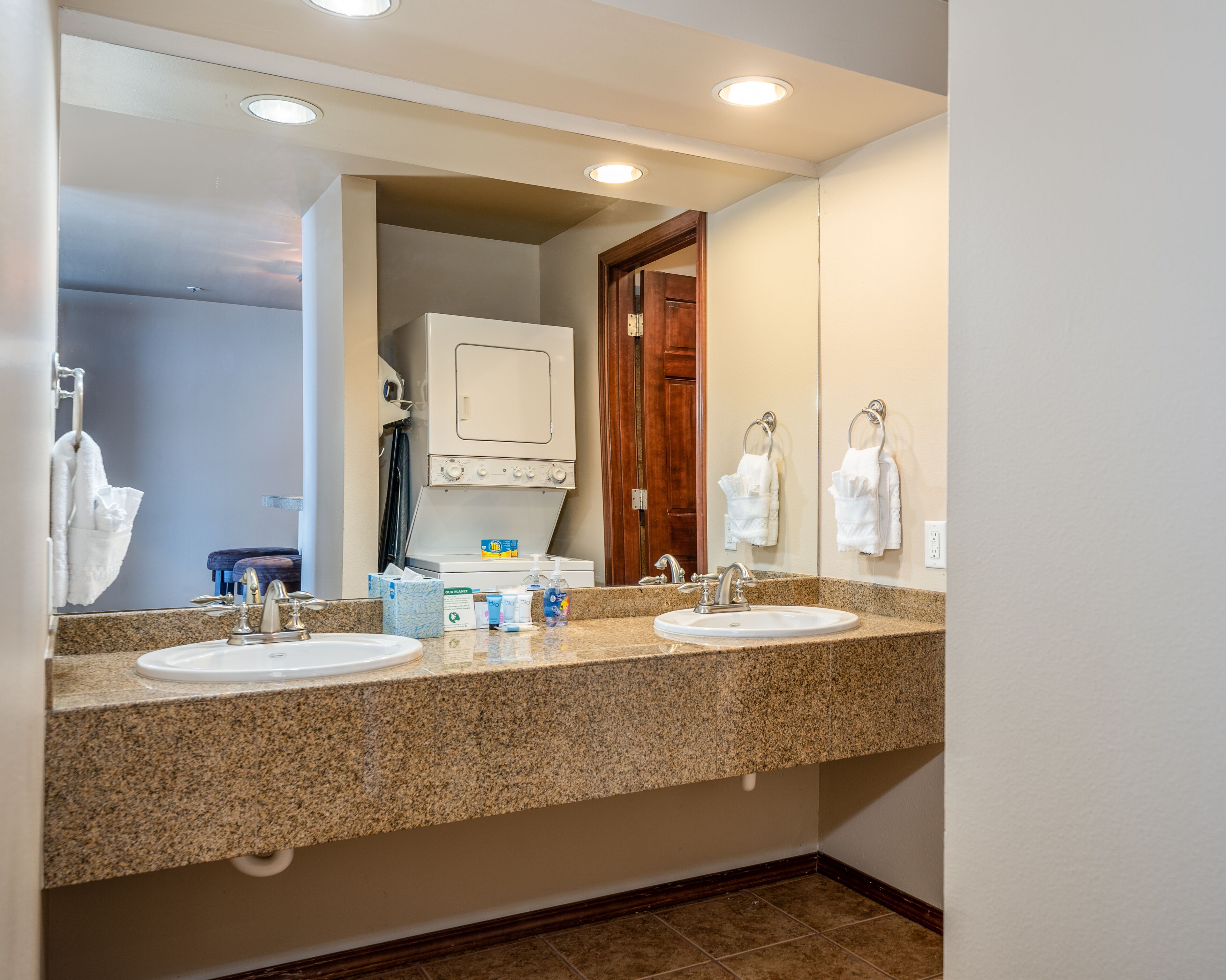 A bathroom with two sinks, a mirror, and a built-in washer and dryer.