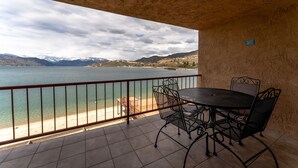 A balcony with a table and chairs overlooking a lake and mountains. - GrandView 305 - Newly Remodeled Waterfront Condo (Chelan)