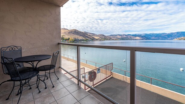 Ein Balkon mit Tisch und Stühlen mit Blick auf einen See und Berge.