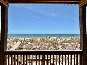 Une terrasse en bois offrant une vue sur la plage et l’océan.