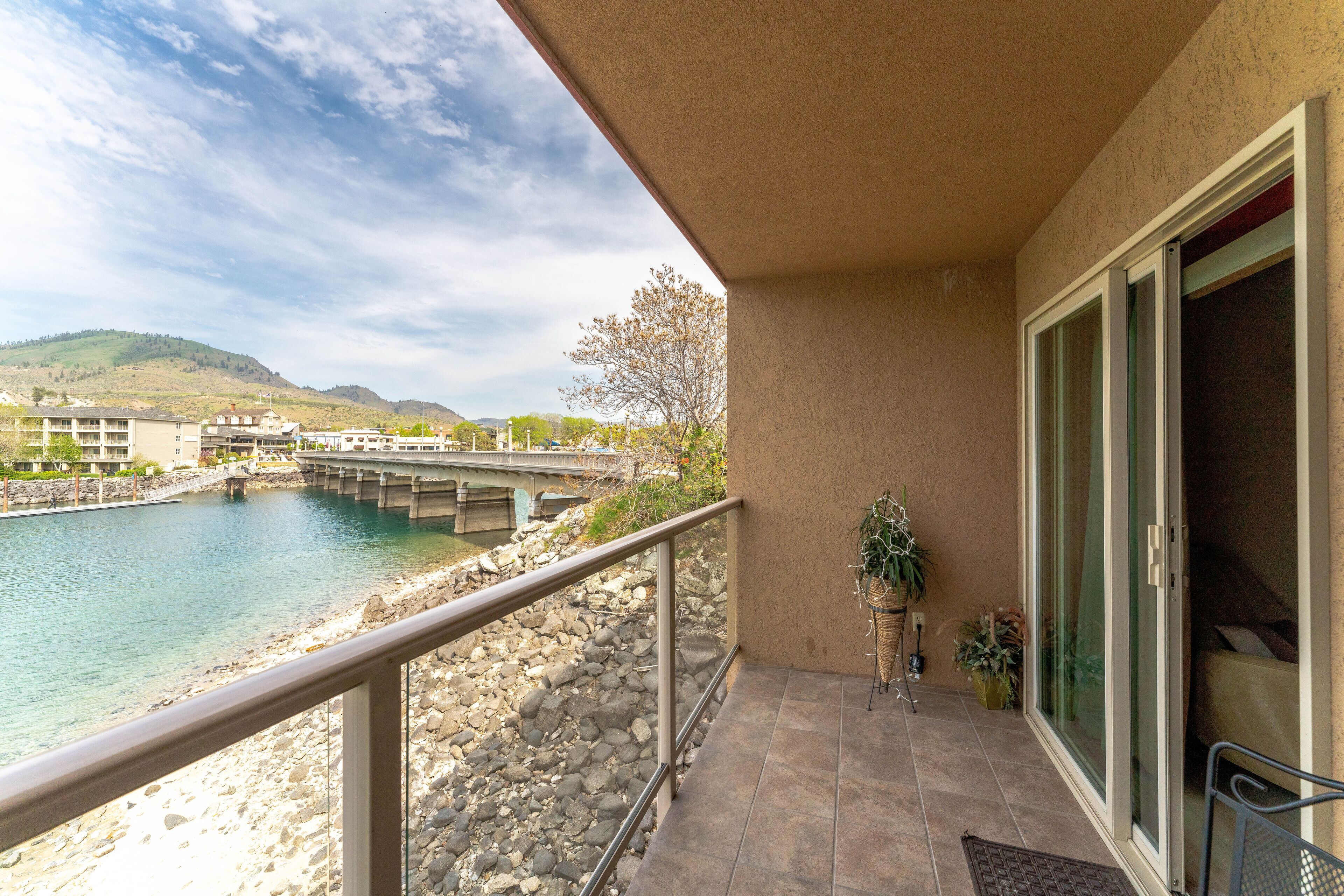 A balcony with a view of a river, a bridge, and a hilly landscape.