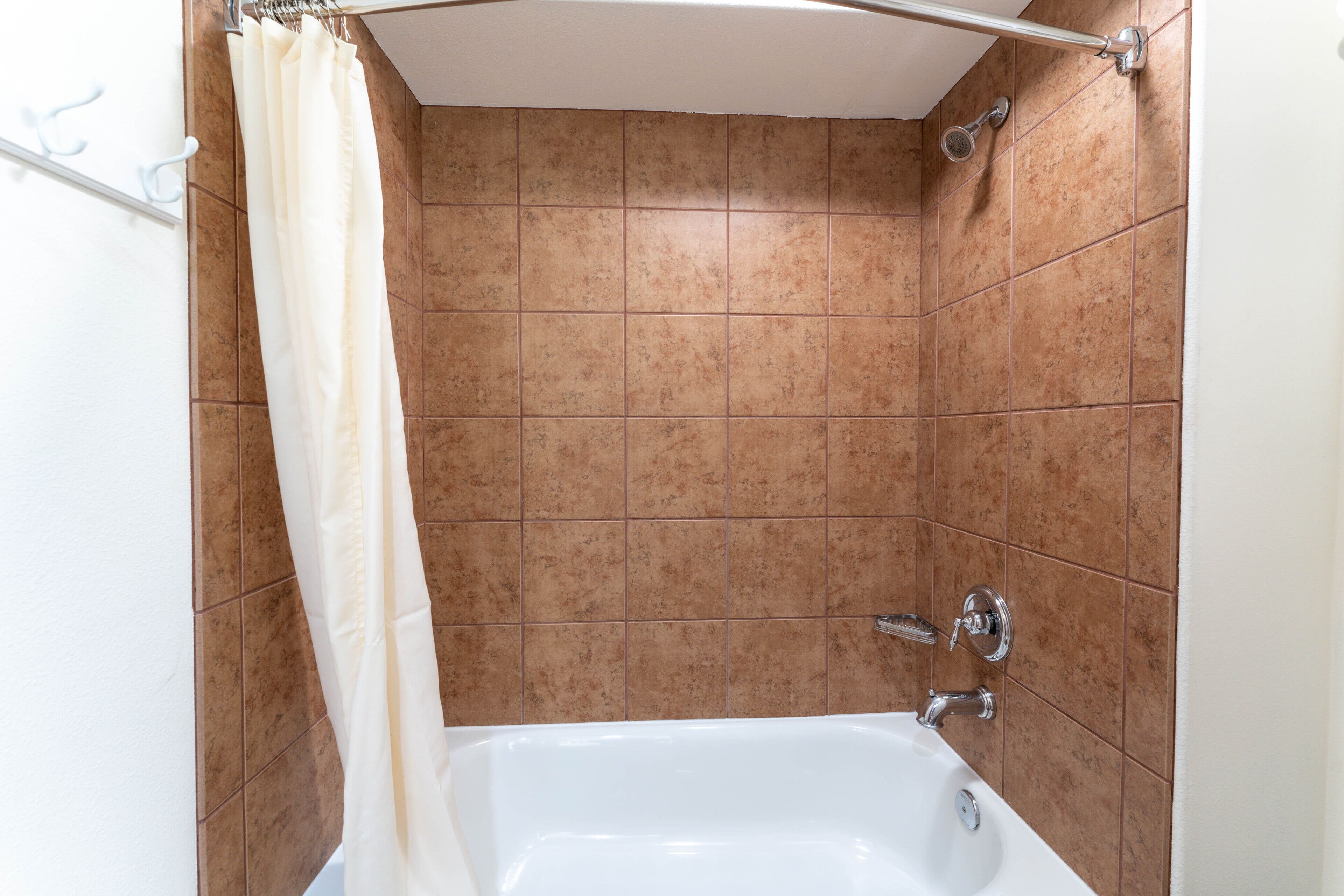 A bathroom with a bathtub, a shower curtain, and tiled walls.
