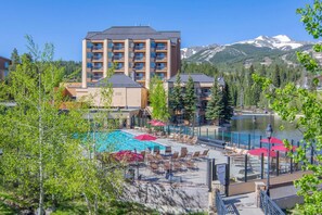 Un hôtel doté d’un espace piscine, entouré d’arbres et avec des montagnes en toile de fond.