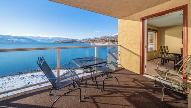 A balcony with a table and chairs, overlooking a lake with mountains in the background. - Grandview 532 Executive Waterfront condo (Chelan)
