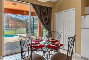 Enjoy meals in this dining area with a glass table and comfortable seating for four, overlooking the outdoor pool.