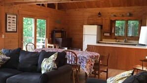 A rustic cabin interior with a dining area, kitchen, and seating with a view of the outdoors. - Waterfront Log Home on Quiet Lake - 25 Minutes -Sunday River Ski (Waterford)