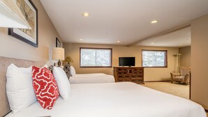 Une chambre d’hôtel avec un grand lit, deux fenêtres, une télévision, une commode et une chaise.