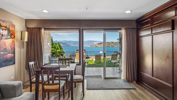Ein Zimmer mit Essbereich, einer Couch und Blick auf einen See und Berge.