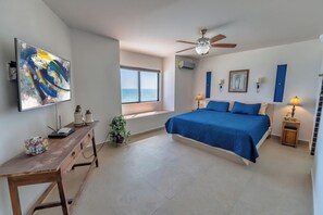 Ein Schlafzimmer mit einem Bett, einem Schreibtisch, einem Fenster und einem Deckenventilator.