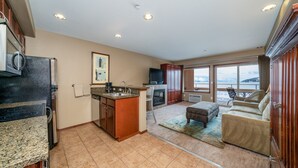 A spacious kitchen with granite countertops, a built-in oven, and a dining area with a sofa and a TV.