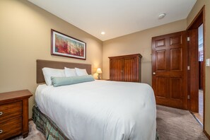 Un dormitorio con una cama grande, un armario de madera, una mesita de noche y un cuadro enmarcado en la pared.