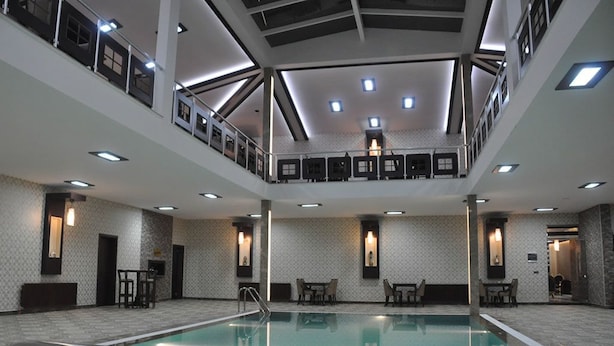 A multi-level indoor swimming pool with a central staircase, multiple seating areas, and a high ceiling with recessed lighting. - Alemdar Otel (Erzincan)