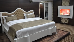 A bedroom with a large bed, a TV mounted on the wall, and a wardrobe. - Alemdar Otel (Erzincan)
