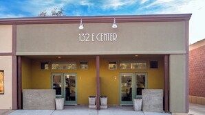Edifici amb el rètol “132 E CENTER” sobre l’entrada. Hi ha dues portes, cadascuna amb una finestra a dalt. La façana de l’edifici és color beix i té detalls marrons.