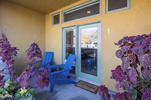 A yellow building with a sliding glass door, blue Adirondack chairs, and purple foliage plants. - Hideaway in the Heart of Downtown Moab #1 (Moab)