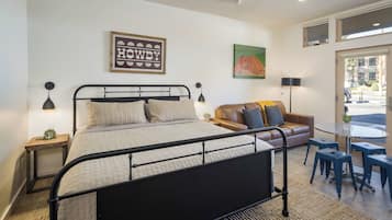 A bedroom with a bed, a sofa, a table, and a chair.