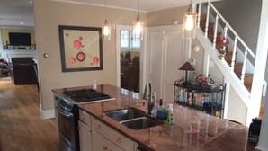 Una cocina con encimeras de granito, electrodomésticos de acero inoxidable y una lámpara colgante.