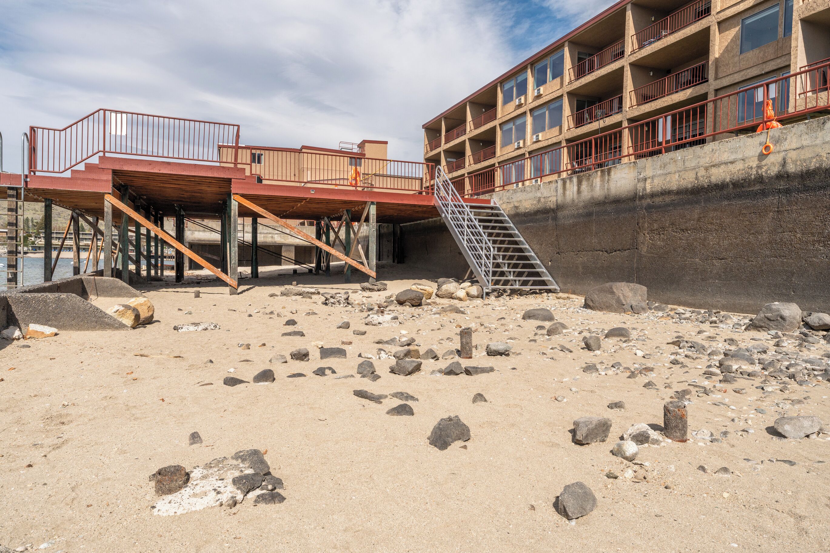 Ein Strandhotel mit Holzterrasse, einer Treppe und einer Betonmauer.