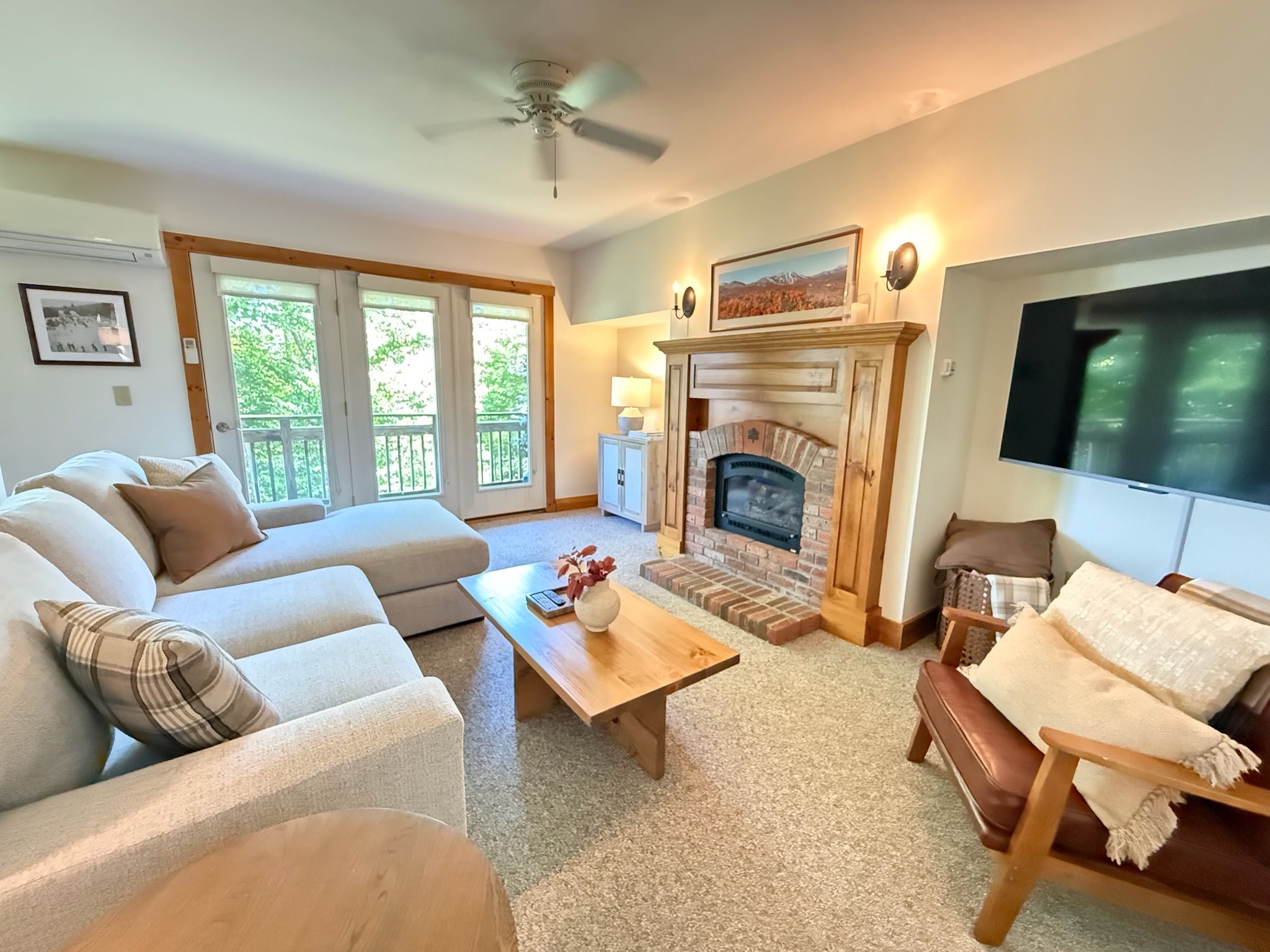 A living room with a fireplace, a sofa, a television, and a ceiling fan.