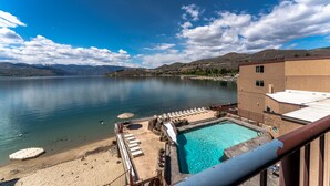 A pool area with lounge chairs and a view of a lake and mountains. - GrandView 401 - 2 Bedroom Waterfront condo (Chelan)
