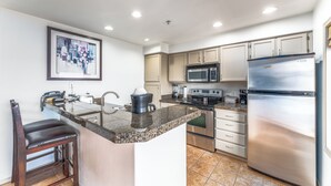 A kitchen with a granite countertop, stainless steel appliances, and a framed picture on the wall. - GrandView 401 - 2 Bedroom Waterfront condo (Chelan)
