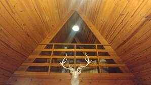 Eine Holzhütte mit einem Satteldach und einem Hirschkopf an der Wand.