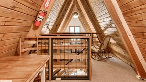Ein Dachzimmer aus Holz mit Feuerlöscher, einem Stuhl und einer Treppe.