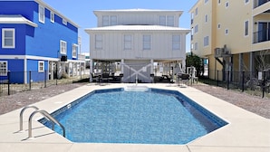 A swimming pool with a metal ladder, surrounded by a fence. There are chairs and tables on the patio area. - Duplex- What if I told you…You CAN afford Paradise! Make the Call today! 🤙 (Gulf Shores)