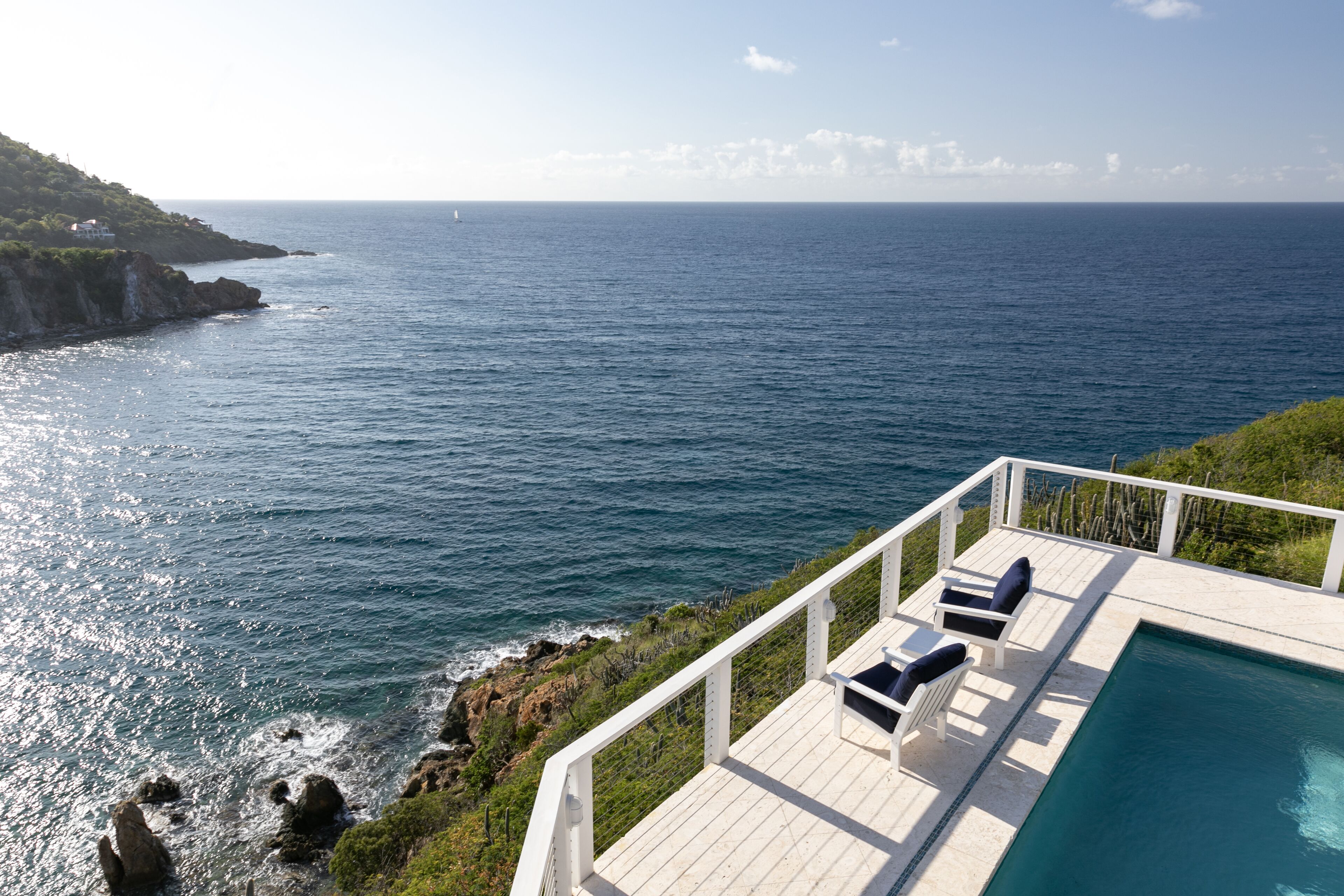 A poolside area with a view of the ocean and a rocky coastline.