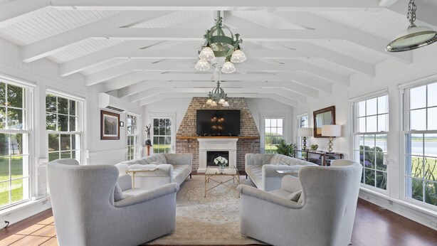 A spacious living room with a fireplace, large windows, and a high ceiling. - Water front home on the Cohansey River (Bridgeton)