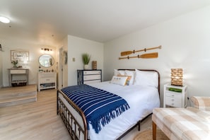 Une chambre à coucher comprenant un lit, des tables de chevet, une commode, un miroir et des éléments fixés au mur.