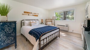 Een slaapkamer met een bed, een dressoir, een raam en een radiator.