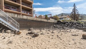 A sandy beach with a concrete staircase leading up to a building with multiple balconies.