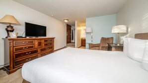 A hotel room with a large bed, a wooden dresser, a television, and a chair.