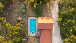 Ein Luftbild eines Anwesens mit Schwimmbad, überdachter Terrasse und einem Gebäude mit rotem Dach.