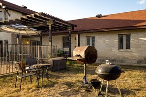 An outdoor patio with a grill, a table, and chairs.